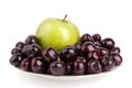 Cherry berries and one big green apple on white plate white background isolated close up macro