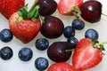 Cherry, berry, strawberry and chopped strawberry on the white floor.