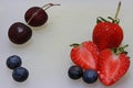 Cherry, berry, strawberry and chopped strawberry on the white floor.