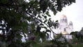 Cherry blossoms on background of Church. Stock footage. Spring bloom of white flowers on green bushes on background of