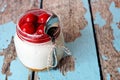 Cherry cheesecake in mason jar with spoon on rustic wood