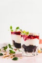 Cherry, cream cheese and chocolate biscuit portion layered dessert in glass, pink background. Black forest trifle. Summer dessert