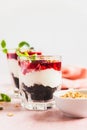 Cherry, cream cheese and chocolate biscuit portion layered dessert in glass, pink background. Black forest trifle. Summer dessert