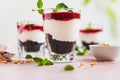 Cherry, cream cheese and chocolate biscuit portion layered dessert in glass, pink background. Black forest trifle. Summer dessert