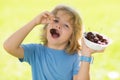 Cherry and cute child. Happy little child with cherry outdoors. Kid picking and eating ripe cherries in summer park