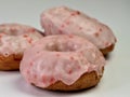 Cherry donuts with pink icing glaze piled up and ready to eat. Up close still life photography shot of 3 donuts