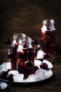 Cherry drink, cold juice with ice in bottles on vintage wooden table, summer fruit cocktail Royalty Free Stock Photo