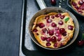 Cherry Dutch Baby, Puff German Pancake on Vintage Pans and Dark Background, Homemade Summer Dessert