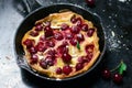 Cherry Dutch Baby, Puff German Pancake on Vintage Pans and Dark Background, Homemade Summer Dessert