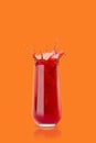 Cherry fresh red juice in glass with reflection, drops and splashind on orange background, copy space, vertical. Vitamin organic Royalty Free Stock Photo