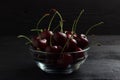 Cherry in a glass plate on a black wooden background Royalty Free Stock Photo