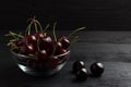 Cherry in a glass plate on a black wooden background Royalty Free Stock Photo