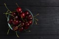 Cherry in a glass plate top view on a black wooden background Royalty Free Stock Photo