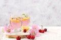 Cherry iced tea or mint and lemon cocktail, a refreshing summer drink recipe. Glass with apple fruit lemonade on light concrete Royalty Free Stock Photo