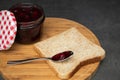 Cherry jam with berries in a glass jar with an open red and white lid next. Next to a wholegrain toast with an empty teaspoon. On Royalty Free Stock Photo