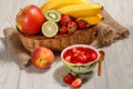 Cherry jelly with strawberry pieces in the bowl, fresh strawberries, nectarine, lime, kiwi, banana, apple in a wicker basket Royalty Free Stock Photo