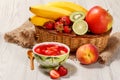 Cherry jelly with strawberry pieces in the bowl, fresh strawberries, nectarine, lime, kiwi, banana, apple in a wicker basket on t Royalty Free Stock Photo