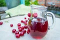 Cherry juice in a carafe, cherries lying on the napkin on the natural outdoor background Royalty Free Stock Photo