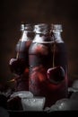 Cherry juice, cold beverage with ice in glass bottles on vintage wooden table, low key, copy space Royalty Free Stock Photo