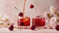 Cherry juice poured into two glasses with ice and cherries falling, bright red summer refreshment Royalty Free Stock Photo
