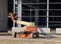 Cherry picker at work on the metallic frame of a modern building under construction.