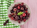 Cherry in a plate on a pink wooden background, towel Royalty Free Stock Photo