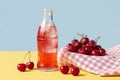 Cherry soda bottle with fresh cherries on checkered cloth Royalty Free Stock Photo