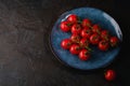 Cherry tomato branch, fresh ripe organic vegetables in blue plate on dark black textured background Royalty Free Stock Photo