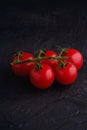 Cherry tomato branch, fresh ripe organic vegetables on dark black textured background Royalty Free Stock Photo