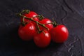 Cherry tomato branch, fresh ripe organic vegetables on dark black textured background Royalty Free Stock Photo