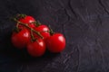 Cherry tomato branch, fresh ripe organic vegetables on dark black textured background Royalty Free Stock Photo