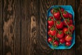 Cherry tomato branches in cardboard packing tray on wooden background