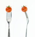 Cherry tomato on fork, front and side view, on white