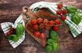 Cherry tomatoes with basil and dish towl on cutting board Royalty Free Stock Photo