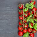 Cherry tomatoes with basil leaves on dark slate background, top Royalty Free Stock Photo