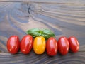 Cherry tomatoes and basil leaves in a spray of water on a wooden background. Selective focus. Local products consumption concept. Royalty Free Stock Photo