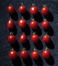 Cherry tomatoes on black background arranged in a linear way.