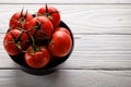 Cherry tomatoes in black bowl on rustic white wooden table, copy space Royalty Free Stock Photo