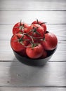 Cherry tomatoes in black bowl on rustic white wooden table, copy space Royalty Free Stock Photo