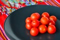 Cherry tomatoes in a black plate over colorful Mexican table top Royalty Free Stock Photo