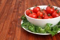 Cherry tomatoes in a bowl surrounded by green mache lettuce