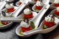 Cherry tomatoes on dessert spoons, garnished with buttercream and sliced olives