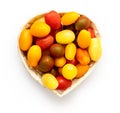 Cherry tomatoes of different colors in the heart shaped woden basket, yellow, orange, red, green