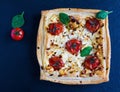 Cherry tomatoes and feta cheese tart made with butter puff pastry. Black stone background, top view Royalty Free Stock Photo