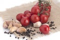 Cherry tomatoes, garlic and black pepper peas on a canvas napkin on a white background Royalty Free Stock Photo