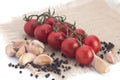 Cherry tomatoes, garlic and black pepper peas on a canvas napkin on a white background Royalty Free Stock Photo