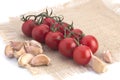 Cherry tomatoes and garlic on a canvas napkin on a white background Royalty Free Stock Photo