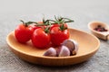 Cherry tomatoes and garlic closeup in a wooden plate on a gray burlap background. Food background. Photo of food side view Royalty Free Stock Photo