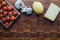 Cherry tomatoes, garlic, lemon and cheese on wooden brownn handmade cutting board