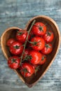 Cherry tomatoes in heart shape plate on old wooden surface, spac Royalty Free Stock Photo